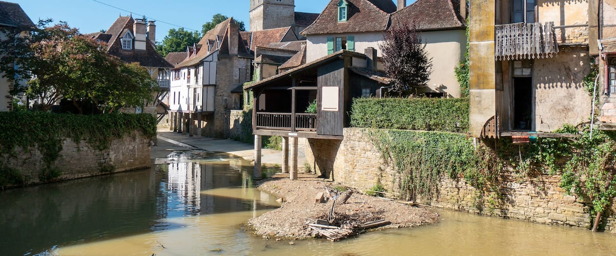 A narrow waterway flanked by historic buildings with steep roofs and a tower.