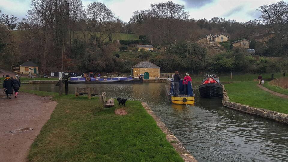 A canal with boats, a small building, and a grassy area with a path.