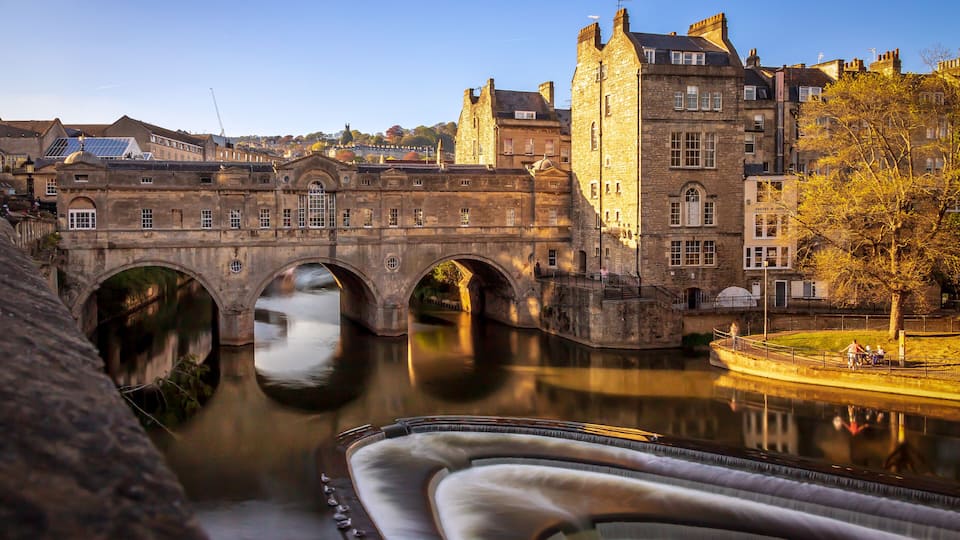 A stone bridge over a river with a castle in the background.