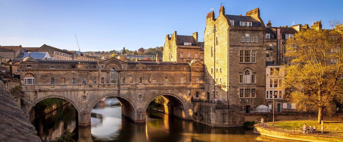 A stone bridge over a river with a castle in the background.