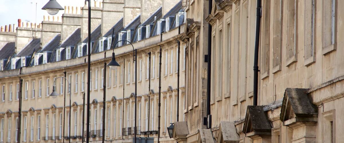 A row of historic buildings with uniform facades and steeply pitched roofs.