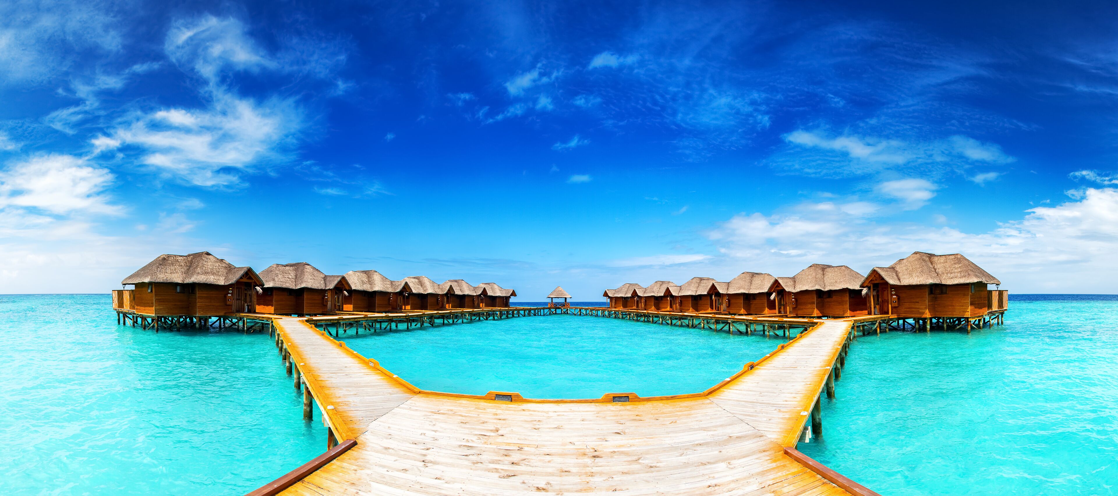Overwater bungalows connected by wooden walkways over turquoise water.