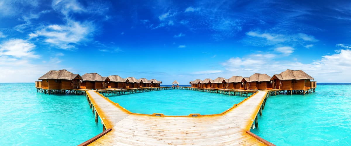 Overwater bungalows connected by wooden walkways over turquoise water.