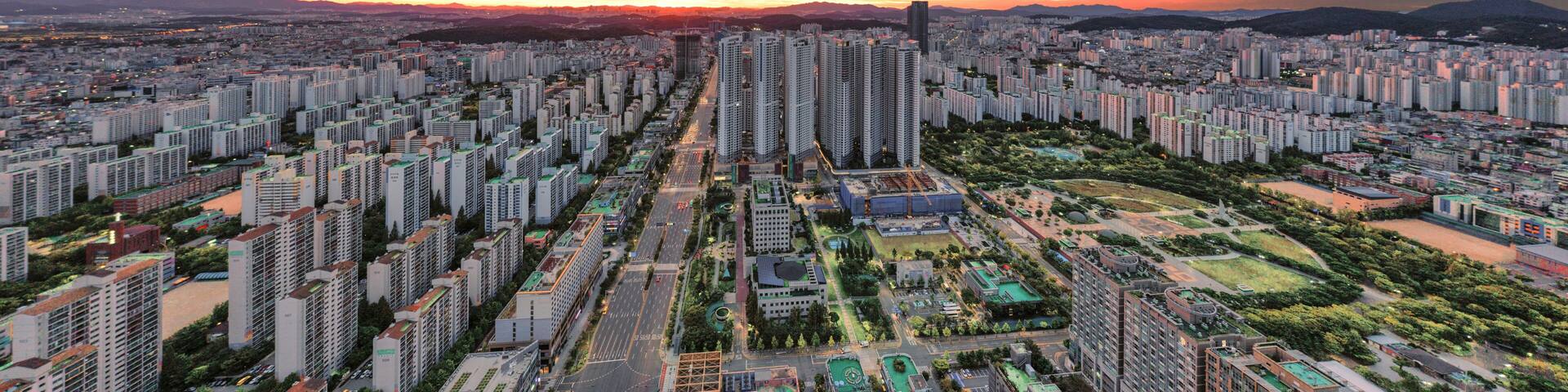 A cityscape with high-rise buildings, a river, and a sunset sky.