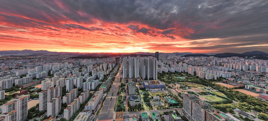 A cityscape with high-rise buildings, a river, and a sunset sky.