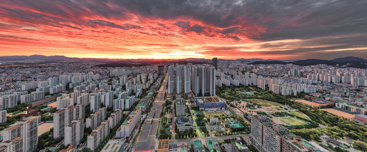 A cityscape with high-rise buildings, a river, and a sunset sky.