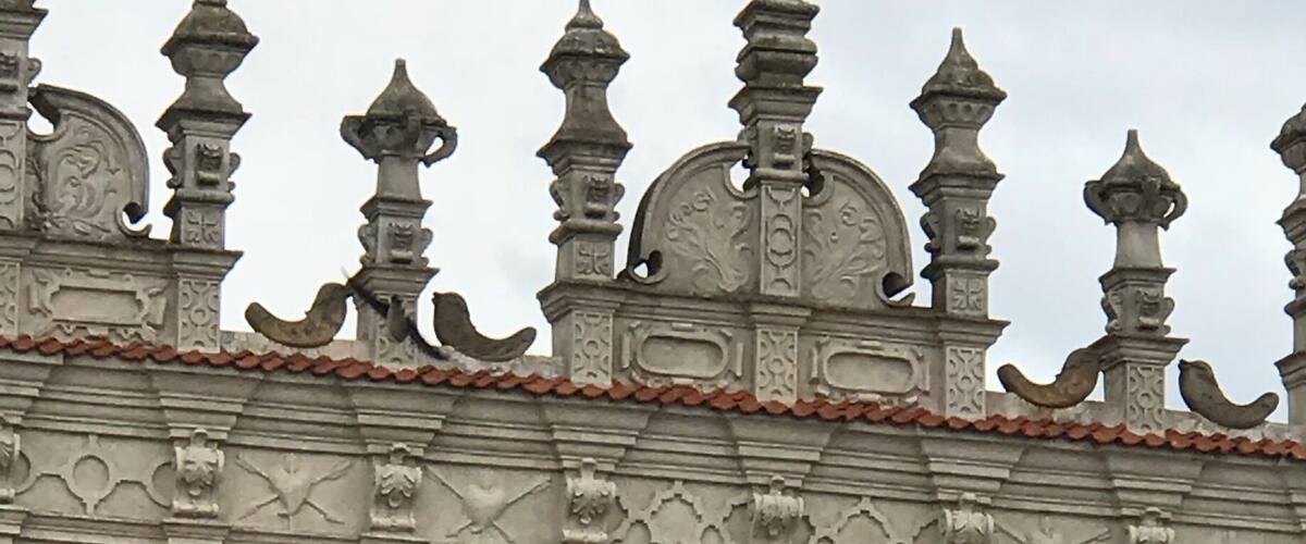 A building with ornate architectural details, including a large relief sculpture of a man and child, and decorative elements on the roof.