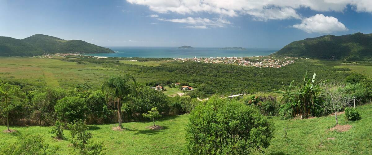 A coastal landscape with lush greenery, a small settlement, and distant islands.