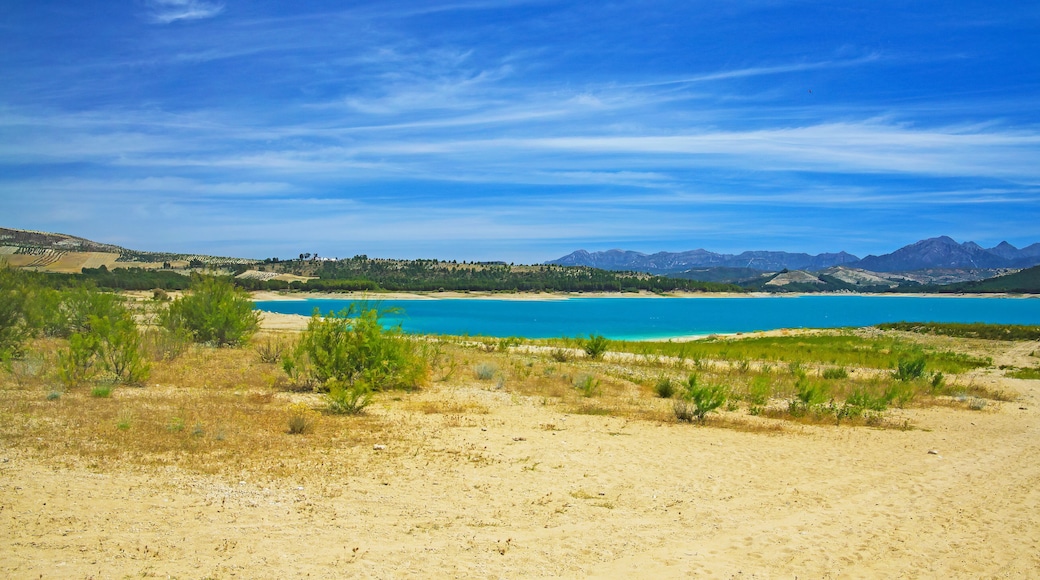 Beautiful idyllic calm blue turquoise mountain swimming lake, empty sand beach - Reservoir Vinuela, Malaga area, Spain