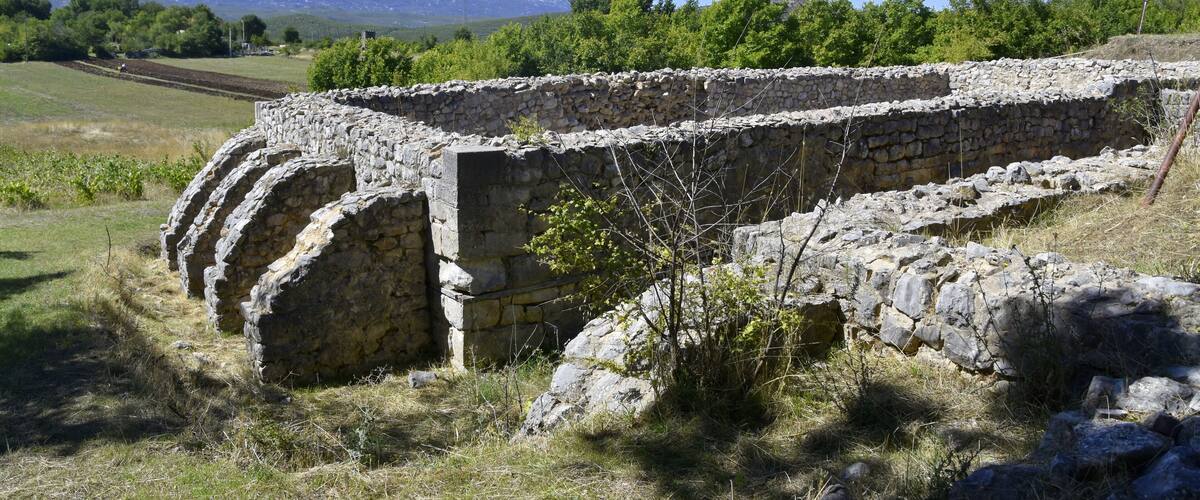 A stone wall with a mountainous backdrop.