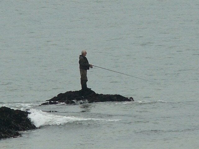 Fishing on a rising tide - look behind you. He did reach dry land but his boots filled up as he left it too late to make a dry escape.
