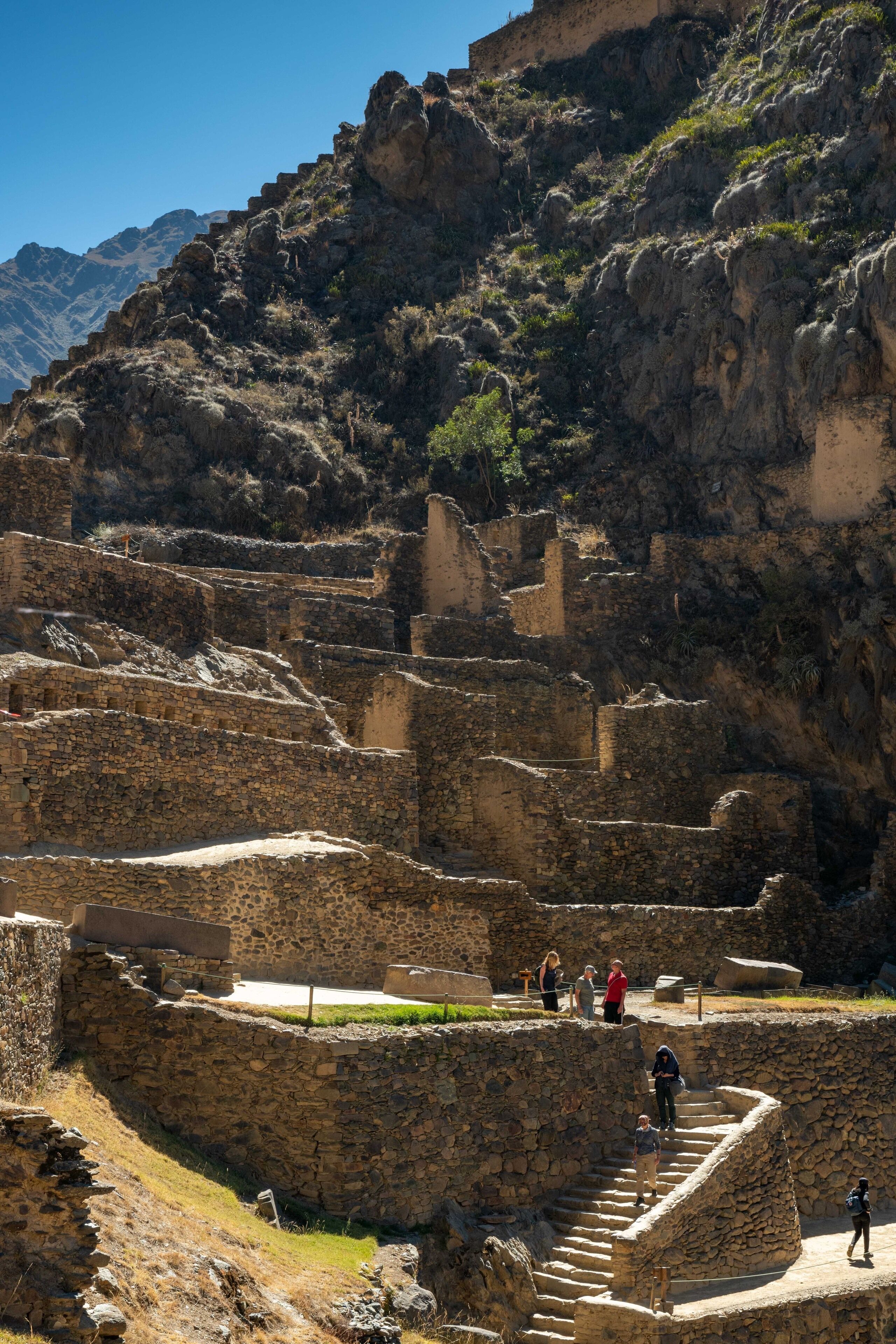 Ancient stone ruins with steps and pathways, surrounded by rocky terrain and sparse vegetation.