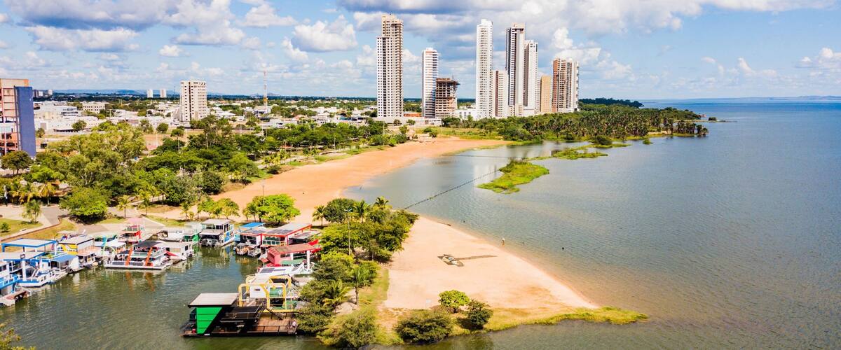 A coastal cityscape with a river, beach, and high-rise buildings.