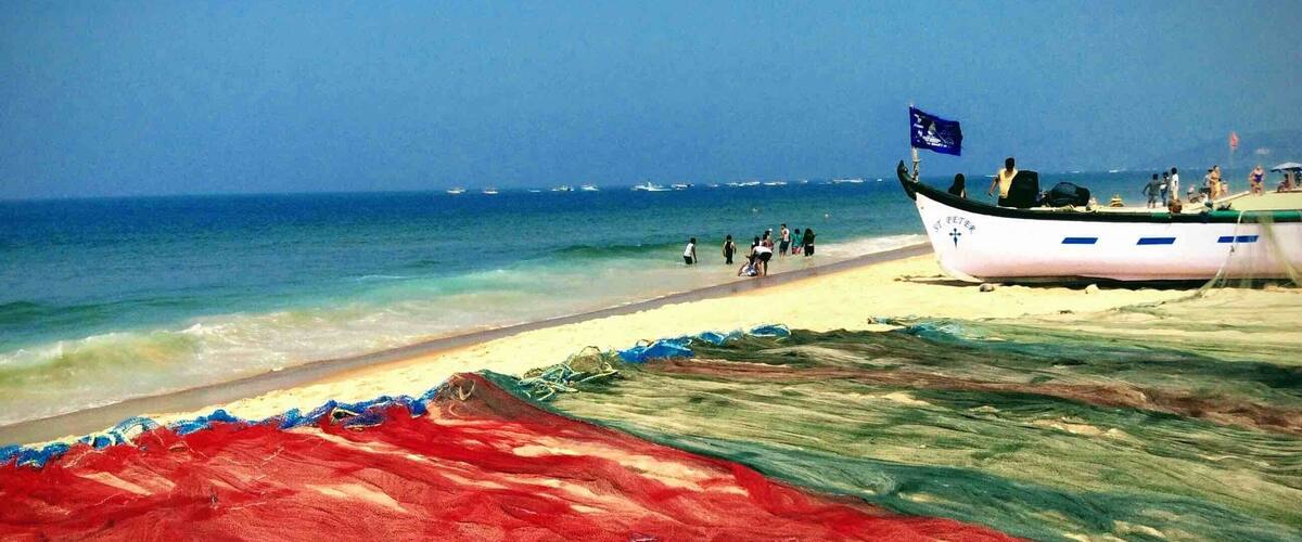 A beach with a boat, people, and a colorful net.