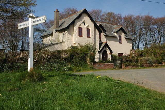 A white house with a signpost indicating directions to Brackley, Sudbury, and Clevedon.