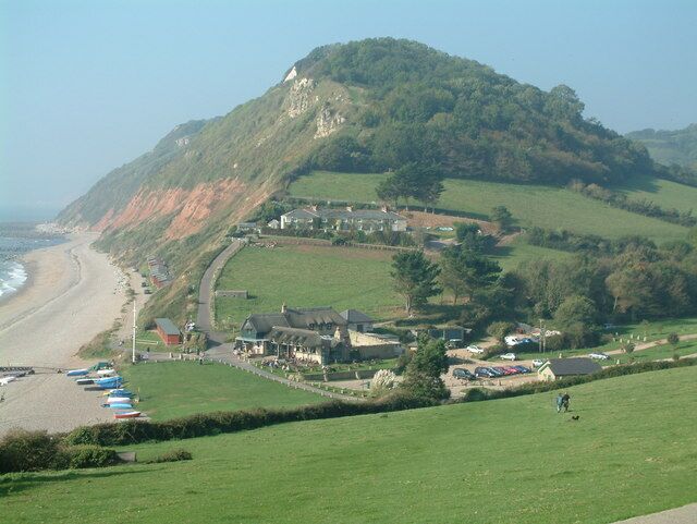 A coastal town with a beach, houses, and a hill.