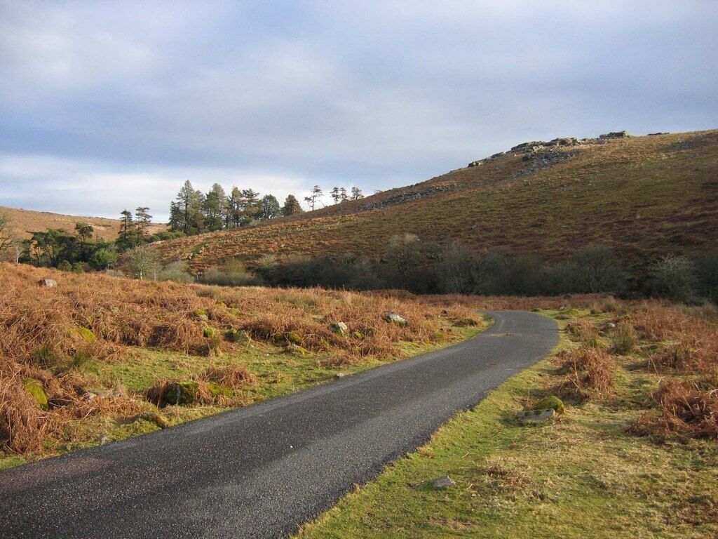 Black Tor. The access road to the Avon Dam leads back towards Shipley bridge, and curls around underneath Black Tor. The trees were planted to shelter Brent Moor House, see 1765058.