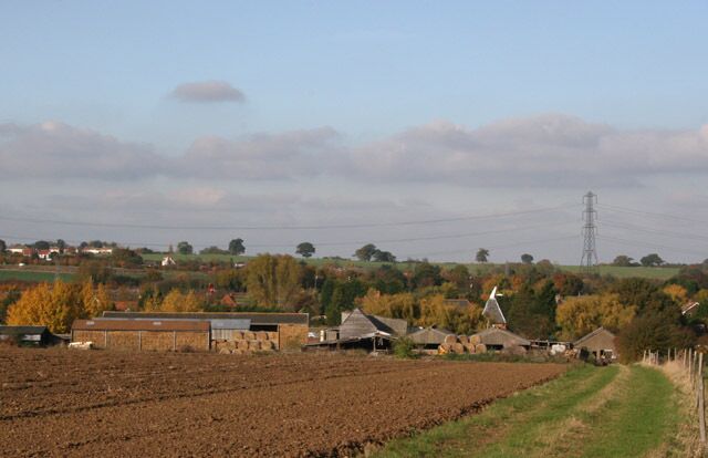 A rural landscape with fields, houses, and a wind turbine.