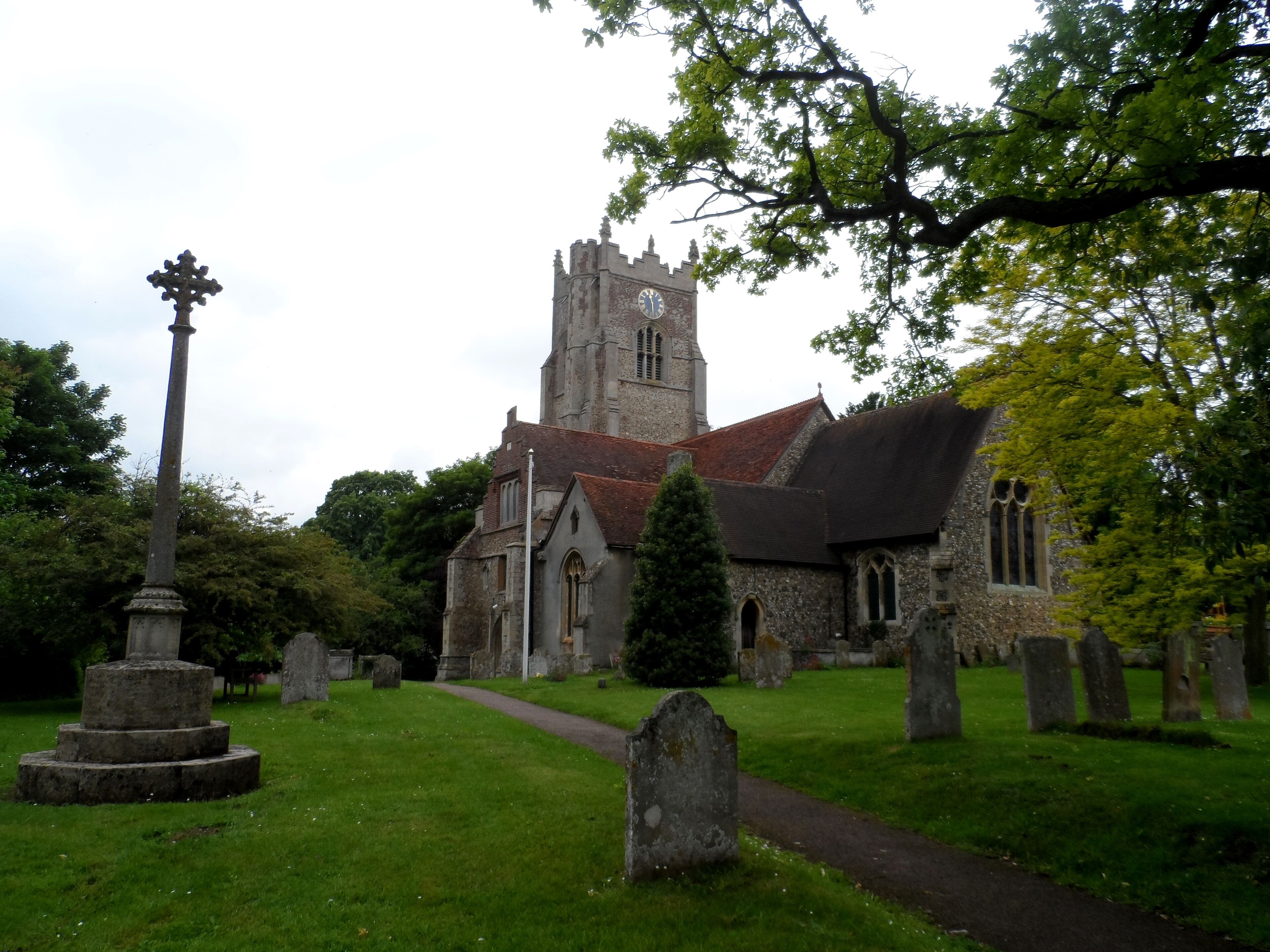 A church with a tall tower and a cross in the foreground.