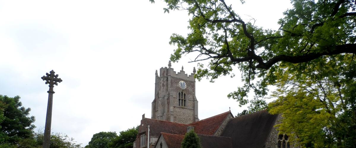 A church with a tall tower and a cross in the foreground.