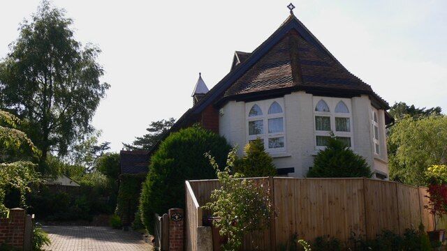 A house with a steeply pitched roof, a white facade, and a brick chimney.