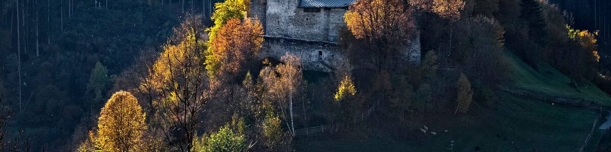 A castle on a hill surrounded by autumn foliage.