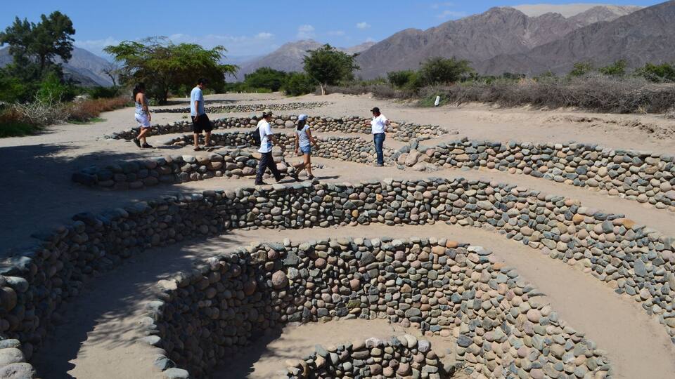 A dry riverbed with stone walls and a group of people walking.