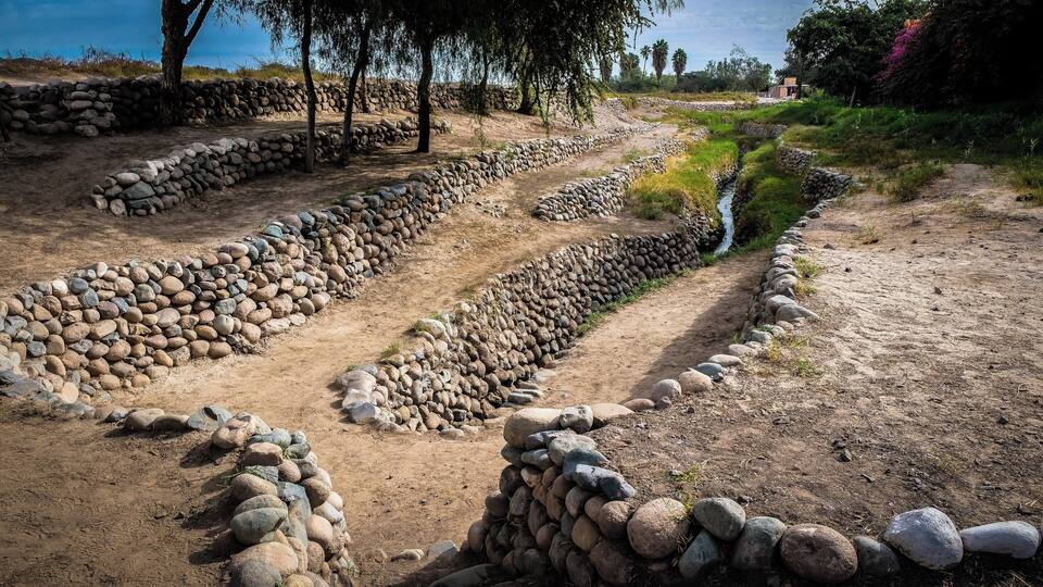 A dry landscape with stone walls and a narrow water channel.