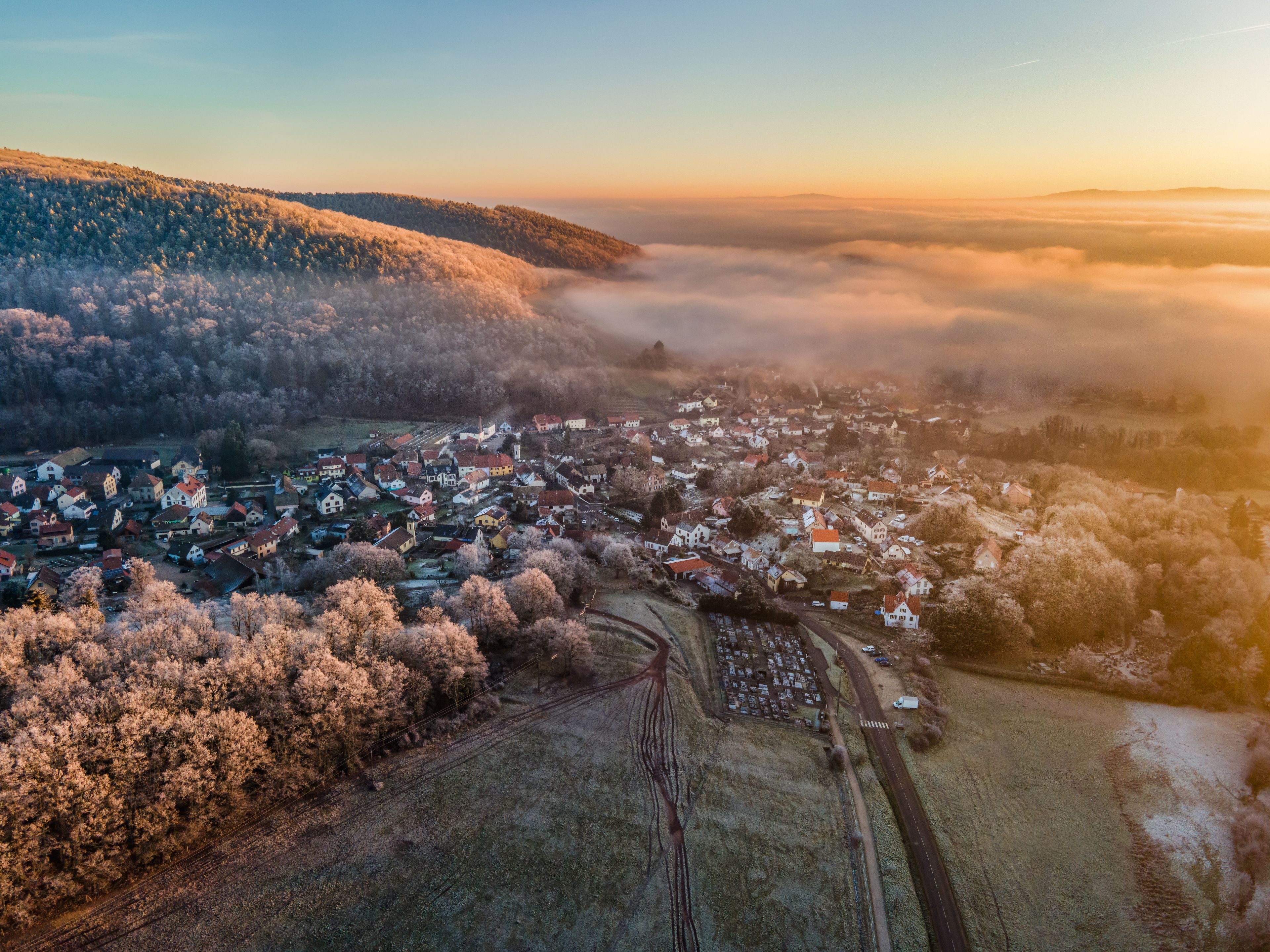 Una cittadina situata in una valle, con una linea ferroviaria, circondata da alberi e colline innevate.