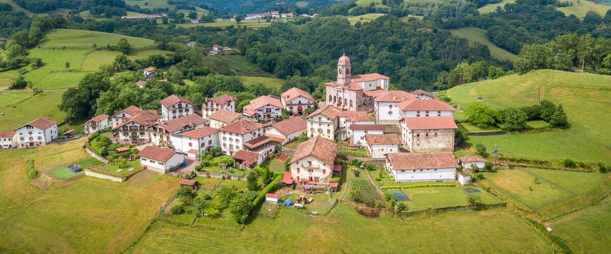 A village with a prominent church and surrounding green hills.
