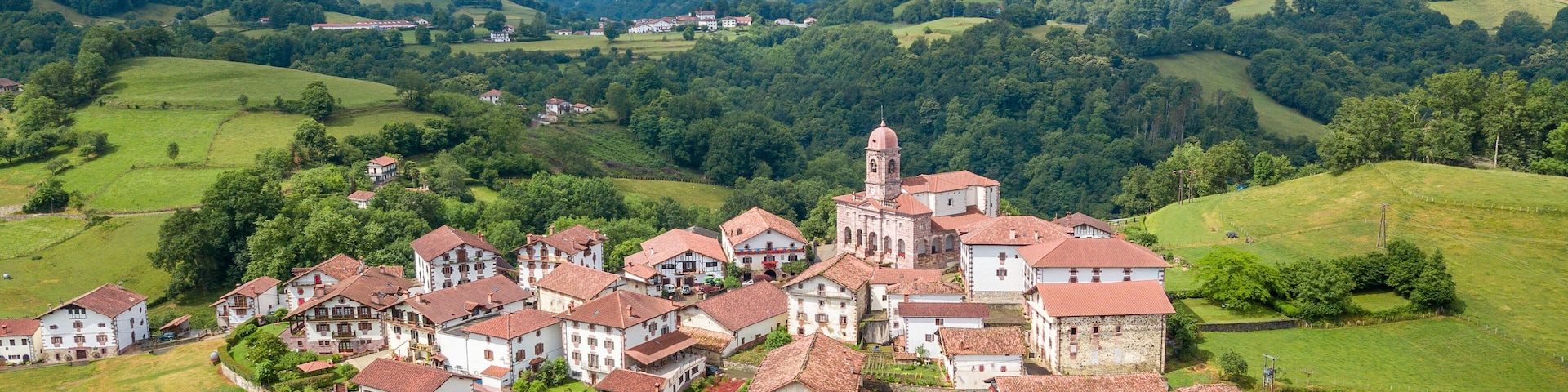 A village with a prominent church and surrounding green hills.