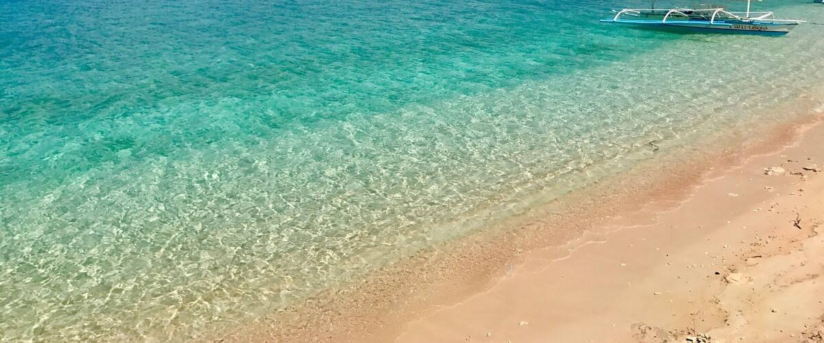 Une mer d’un bleu turquoise éclatant, une plage de sable fin et un bateau appelé WINDSOR.
