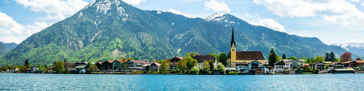 Eine Stadt am See mit einer Kirche und Bergen im Hintergrund.