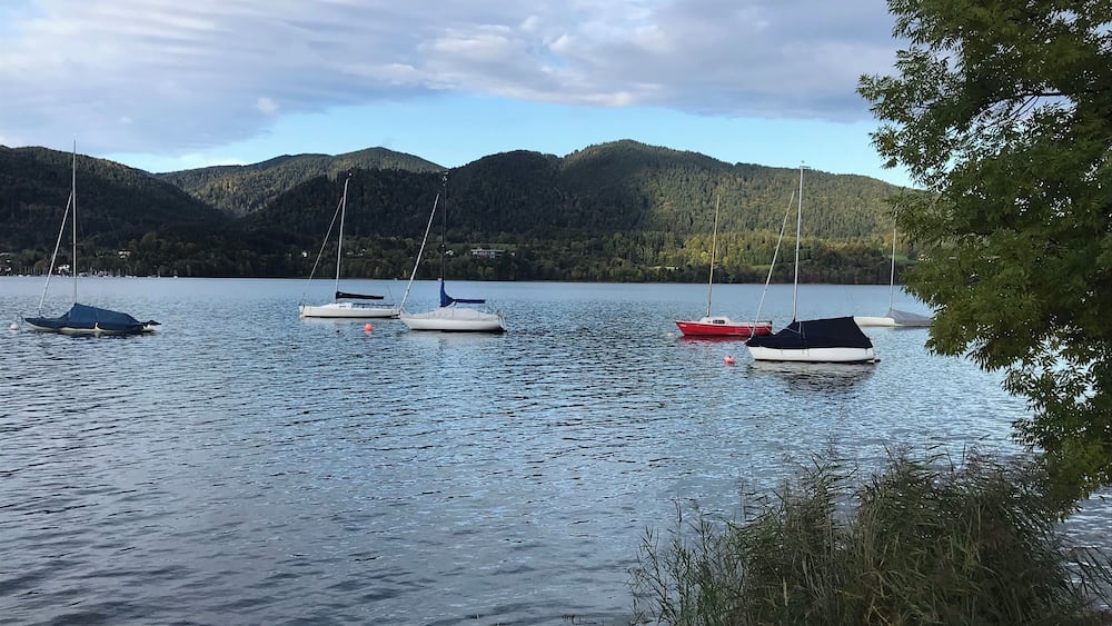 Ein ruhiger See mit mehreren ankernden Segelbooten.