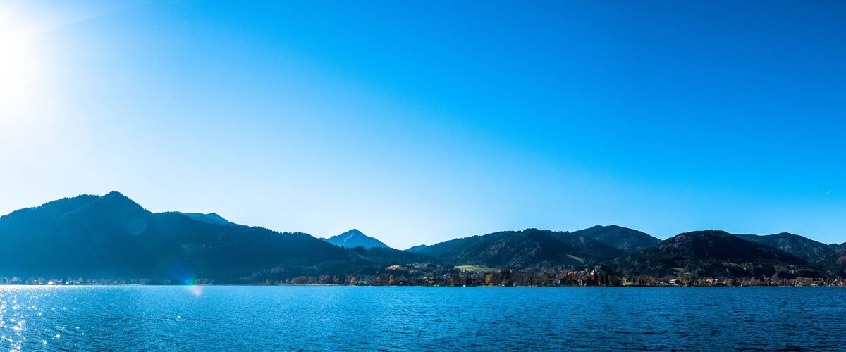 A mountain range with a lake in the foreground and a clear sky.