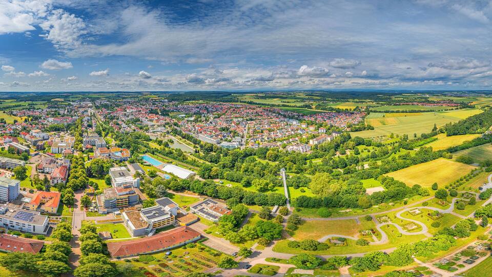A town with a central square, surrounded by green fields and a river.