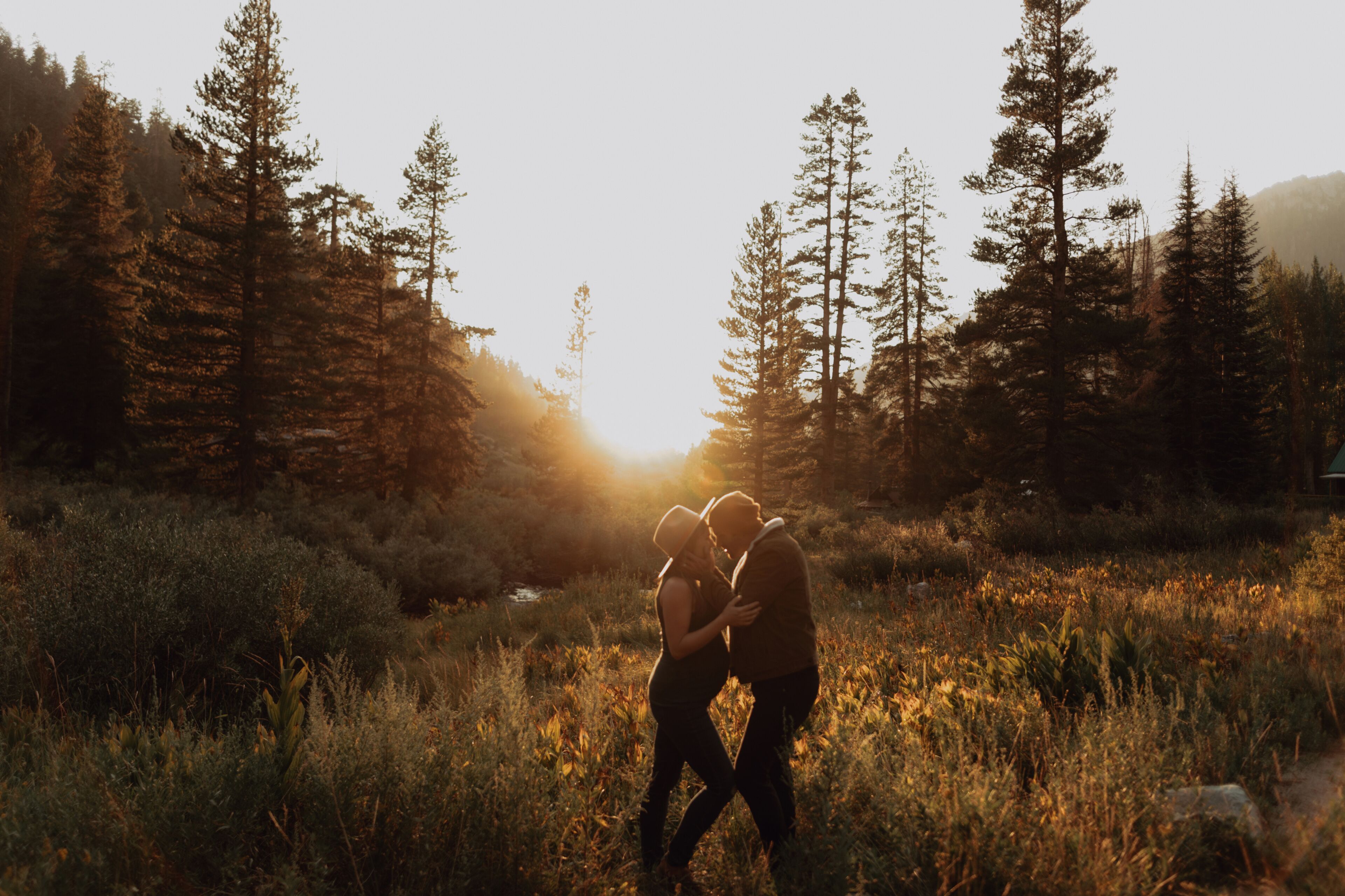 Pregnant mid adult couple face to face in rural valley at sunset, Mineral King, California, USA