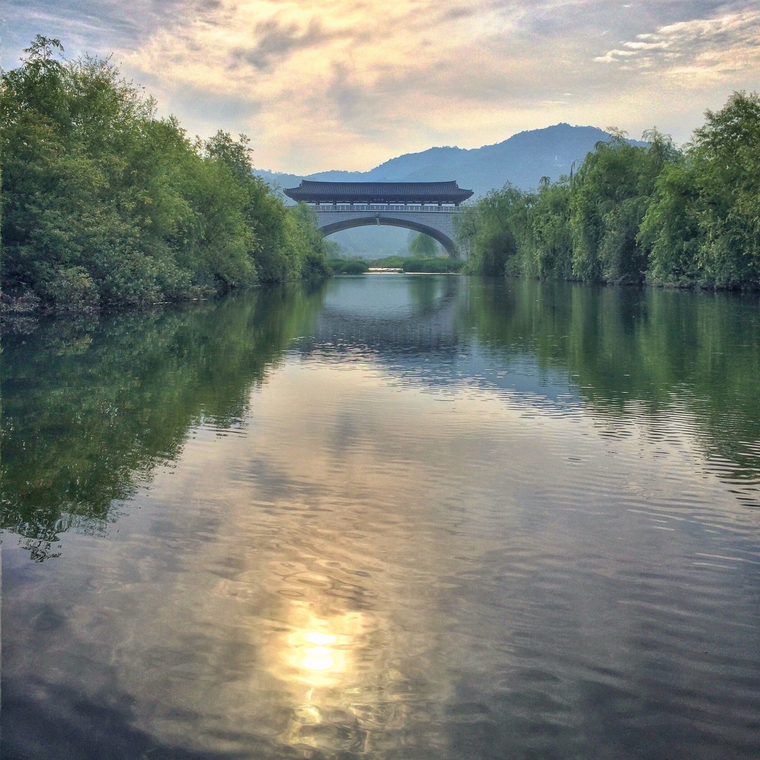 Un río tranquilo con un puente y montañas al fondo.