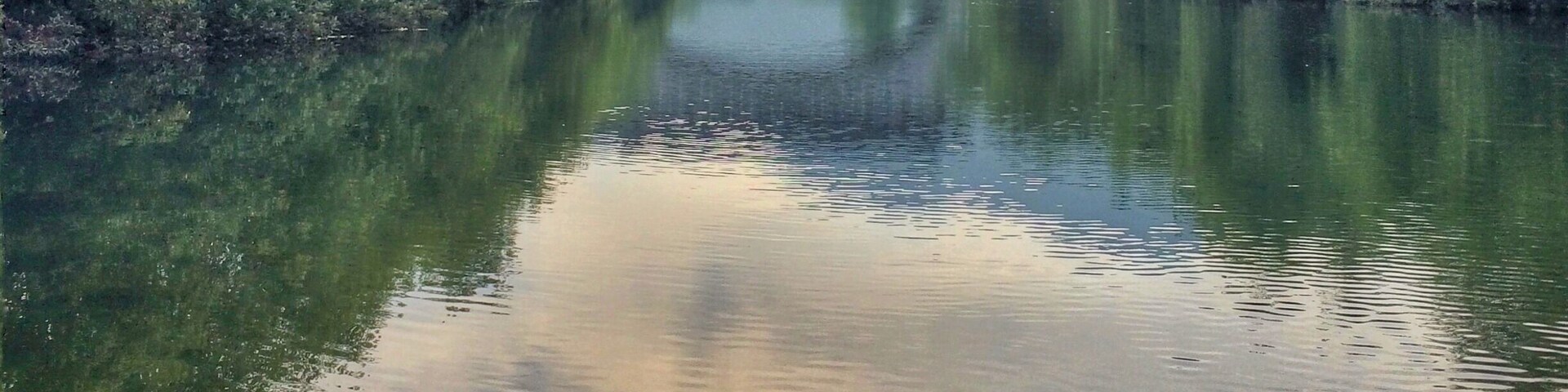 Un río tranquilo con un puente y montañas al fondo.