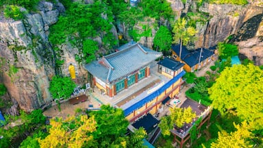 A traditional Chinese building nestled in a lush, mountainous area with steep cliffs and dense greenery.