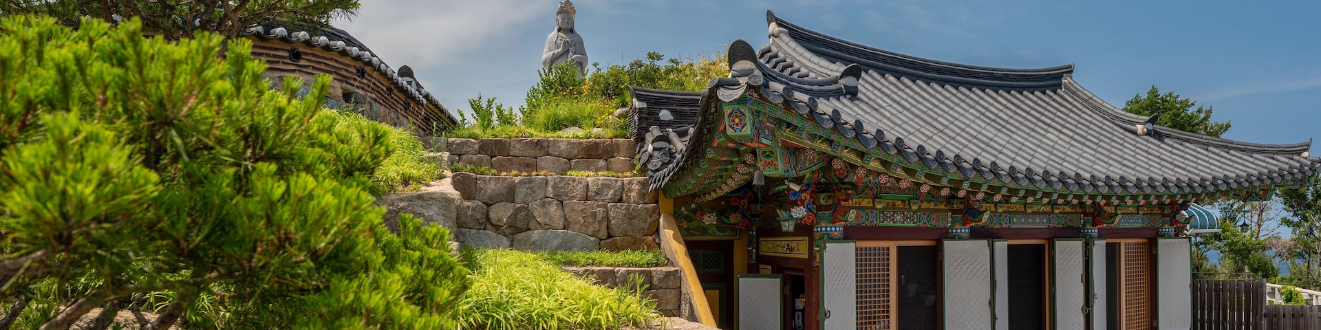 A traditional Korean temple with ornate architecture, a stone pathway, and a statue in the background.