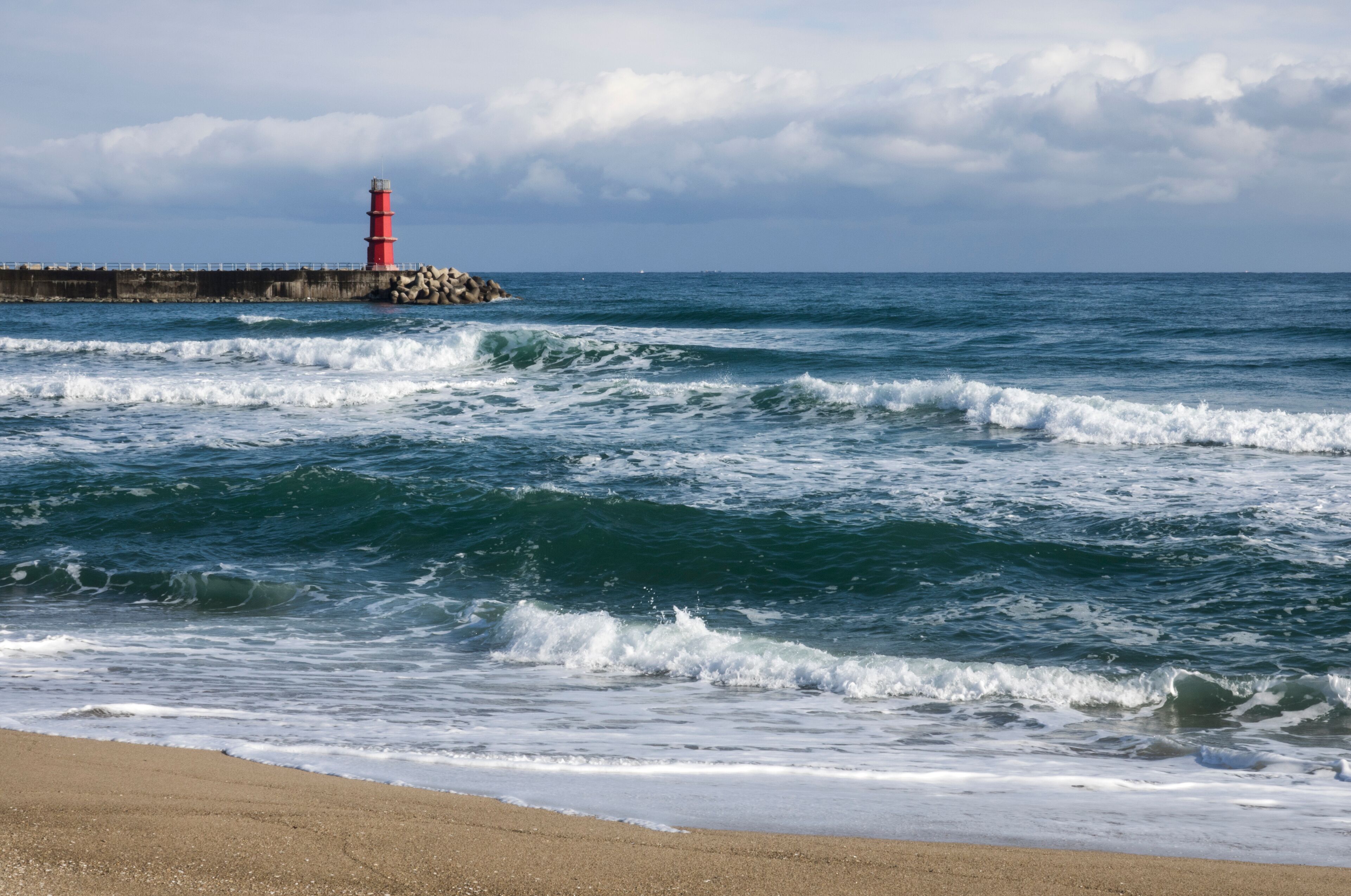 View of the surfs against the seawall and lighthouse