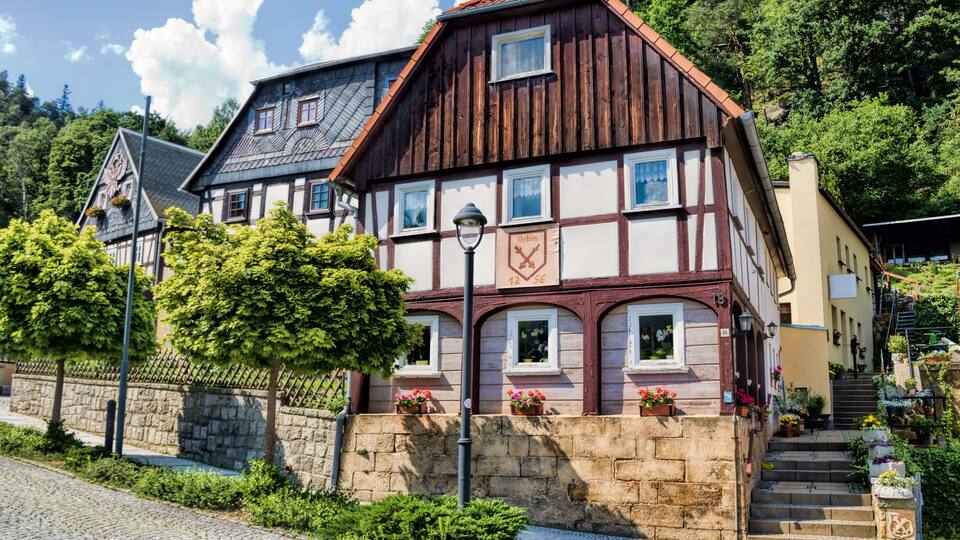 A traditional half-timbered house with a stone wall and a clock.