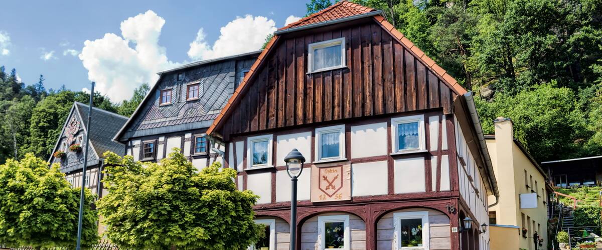 A traditional half-timbered house with a stone wall and a clock.