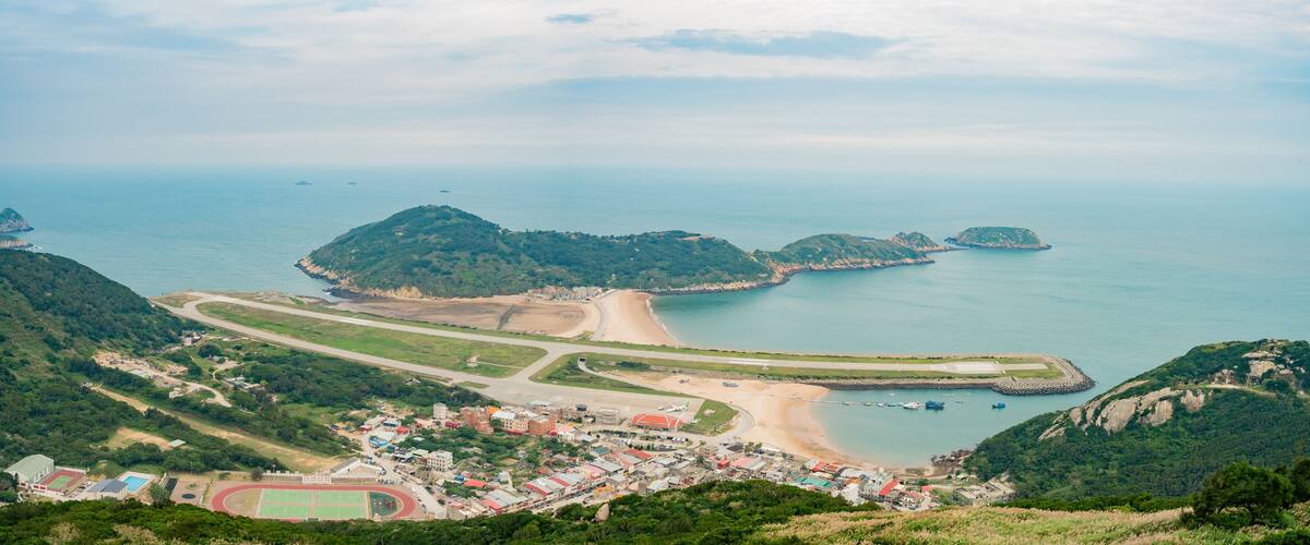 A coastal town with a beach, a small airport, and surrounding hills.