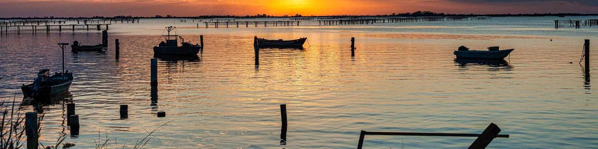 Breathtaking sunset in Po Delta with Stilts and fishingboats , Italy
