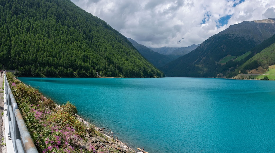 A turquoise lake surrounded by mountains, with a small village and a church on the right.