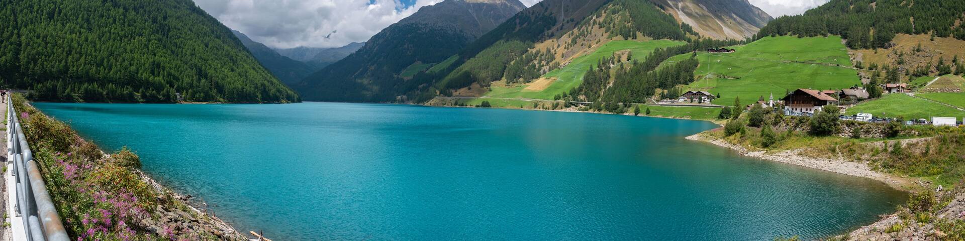 A turquoise lake surrounded by mountains, with a small village and a church on the right.