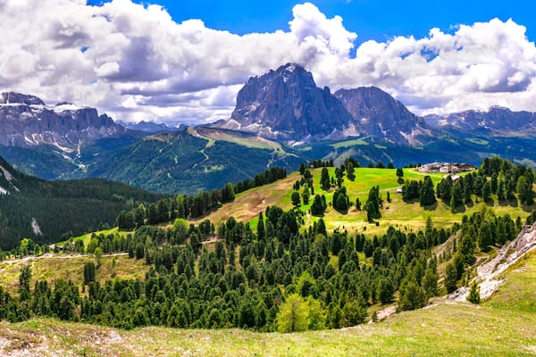 Eine gebirgige Landschaft mit blauem Himmel, einem gewundenen Pfad und einem GebĂ€ude auf einem HĂŒgel.