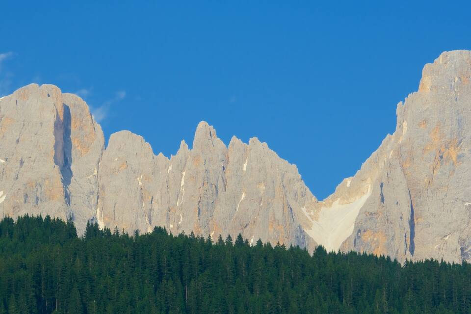 A mountain range with sharp peaks and a forested base.